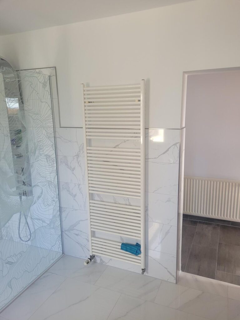 Ein modernes Badezimmer mit einem weißen Handtuchheizkörper an der Wand.